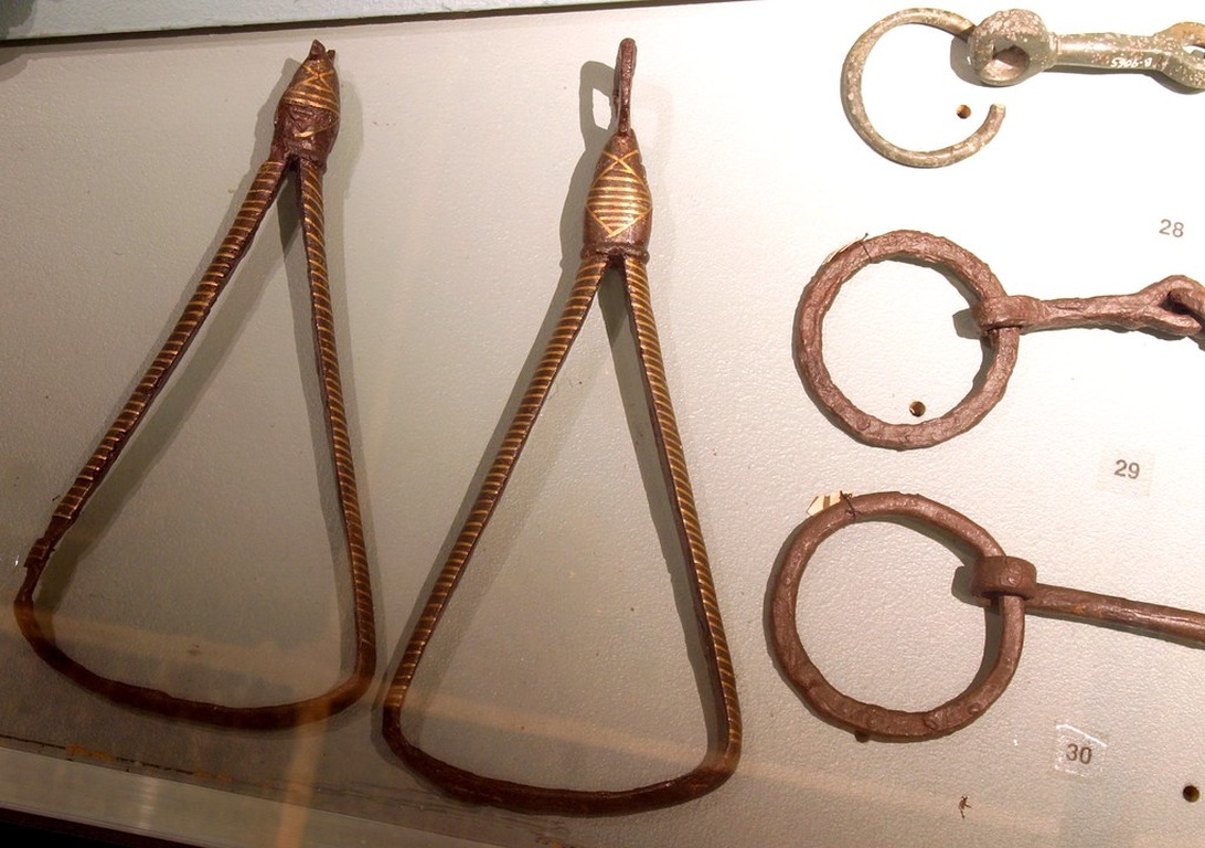 En museiutställning med antik hästutrustning, inklusive dekorativa bett i metall.